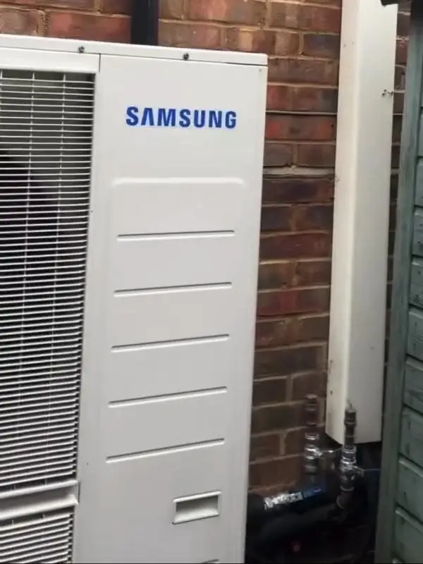 Samsung air source heat pump outdoor unit beside a brick house