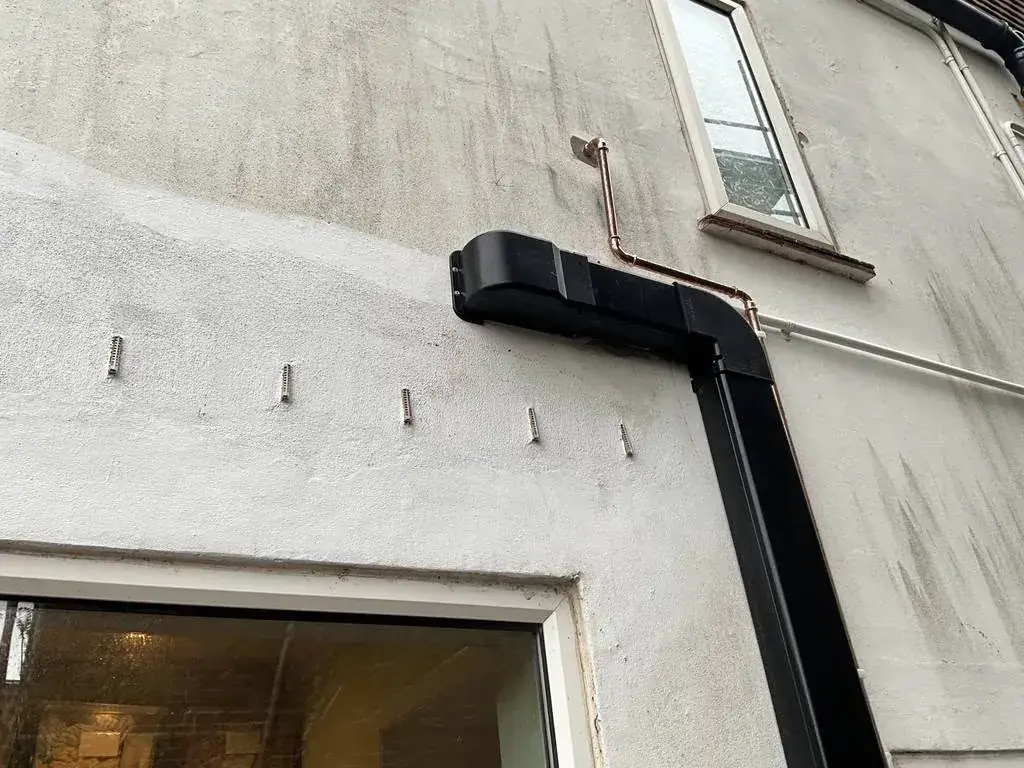 Heat pump pipework running in black StrutFast trunking on an external wall in Hove